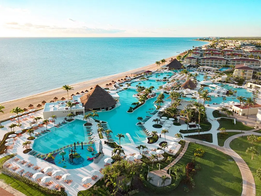 Aerial view of the enormous Sunrise pool, children's splash area, tropical grounds, and beachfront at Moon Palace Cancun